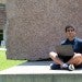 Rishi Madhuvairy sits with laptop in front of the O'Connor building
